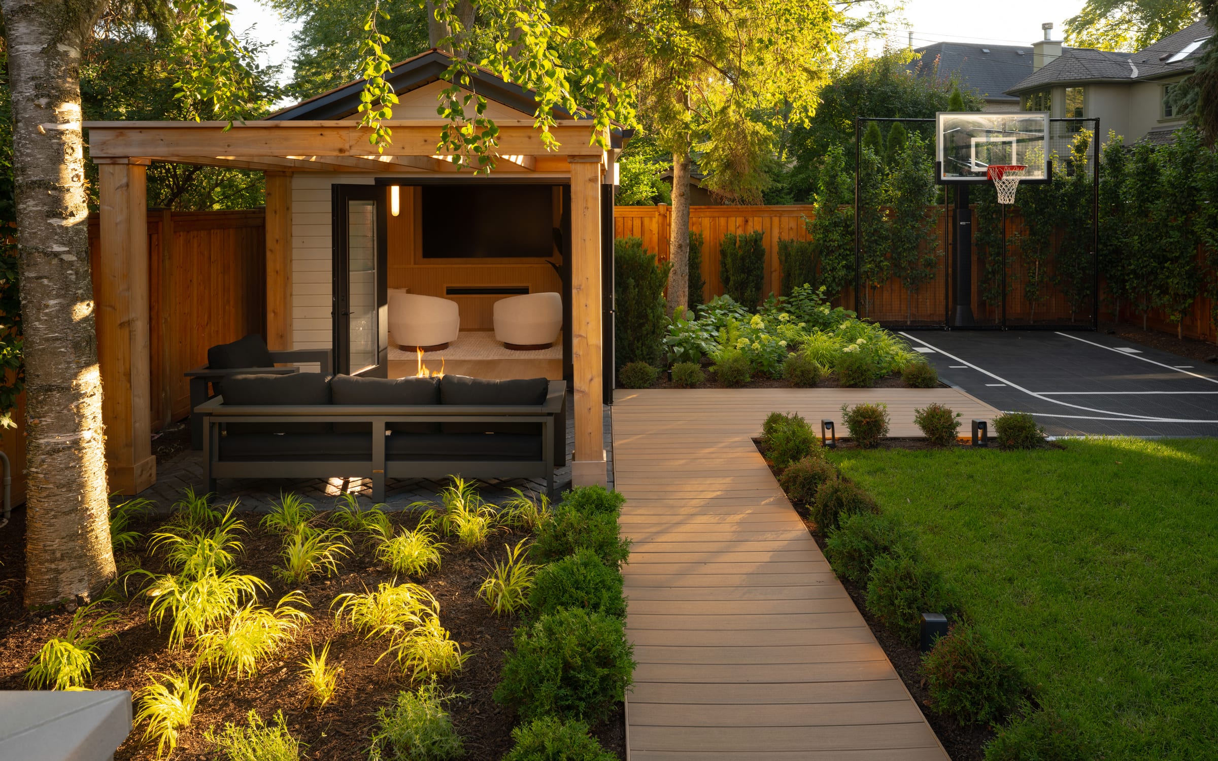 A Zing backyard build with cabana, outdoor lounge and sport court at dusk
